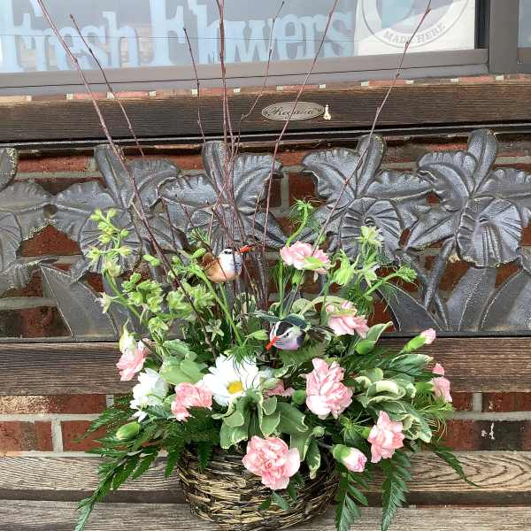 Basket arrangement with pink carnations, white daisies, and bird decorations