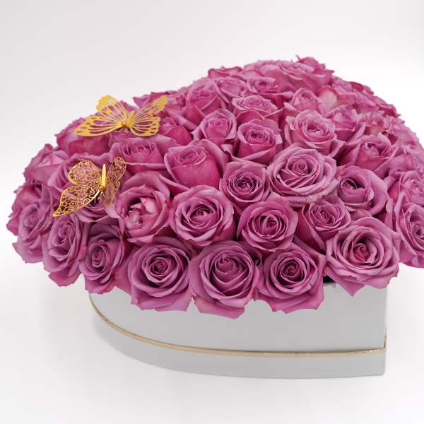 Heart-shaped box filled with pink roses and two gold butterfly decorations