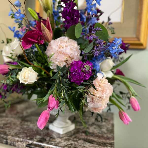 Colorful mixed flower arrangement in a white pedestal vase
