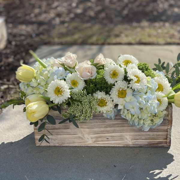 Rectangular wooden box arrangement with white daisies, pale roses, hydrangeas, and yellow tulips