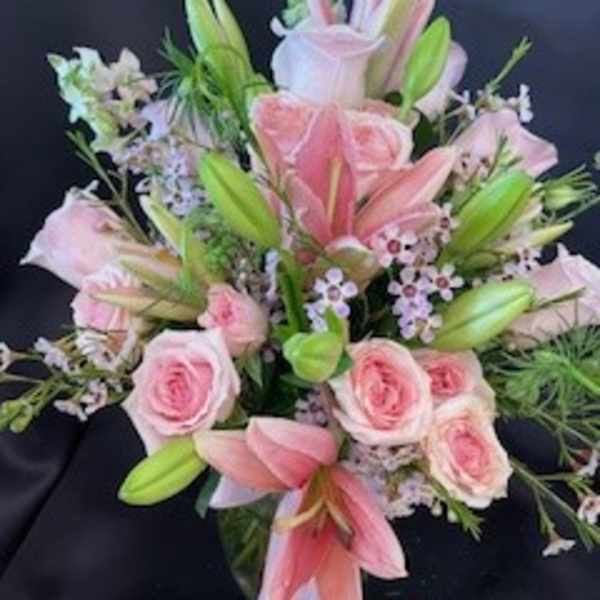 Pink lilies and roses arranged with small filler flowers
