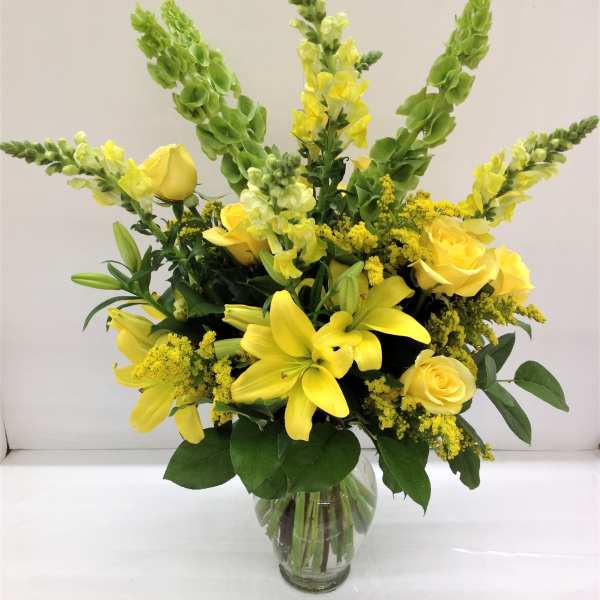 Yellow roses and lilies in a clear glass vase
