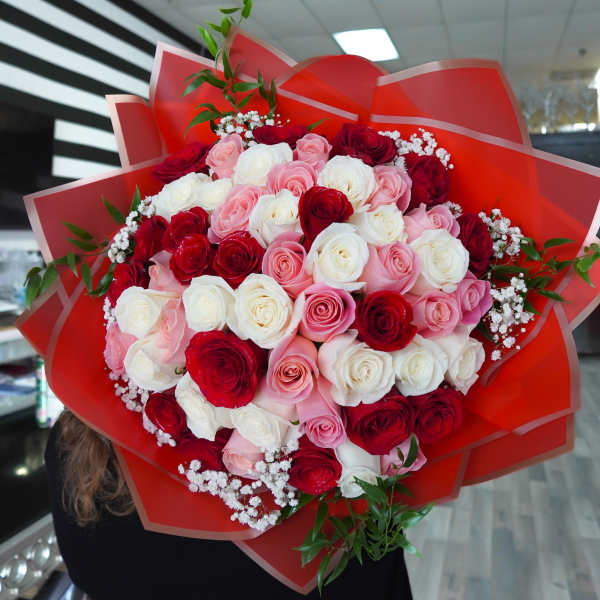 Large bouquet of red, pink, and white roses wrapped in red paper