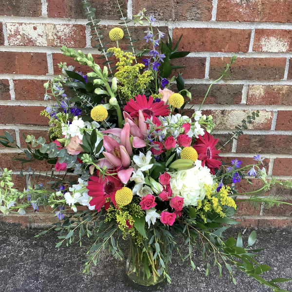 Mixed bouquet in a glass vase with pink lilies, gerbera daisies, roses, and white blooms