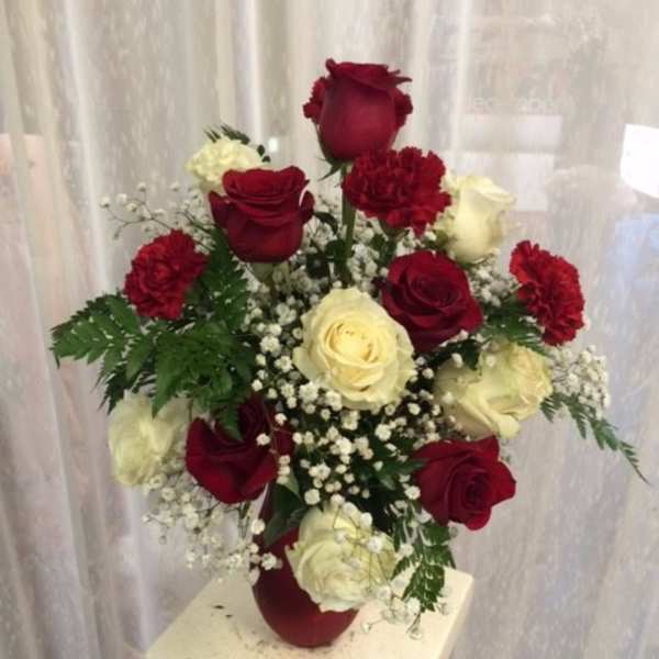 Red and white roses arranged in a vase with baby's breath