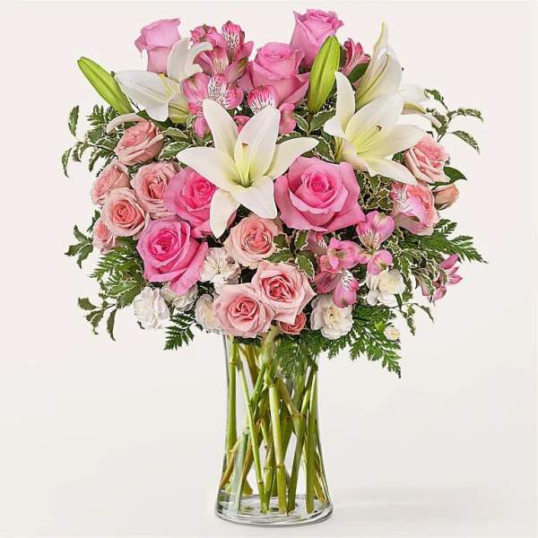 Pink roses and white lilies arranged in a clear glass vase