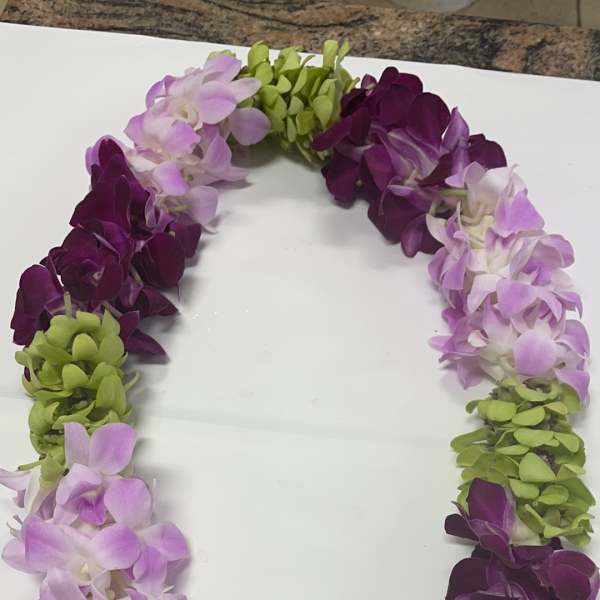 Purple, lavender, and green orchid lei on a white surface