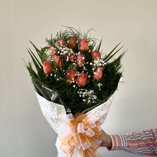 Bouquet of coral roses with baby's breath and a large ribbon