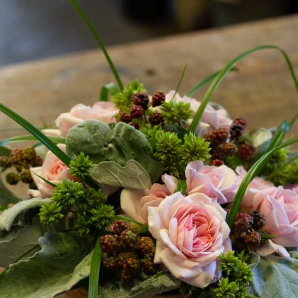 Pink roses arranged in a low bowl with green accents