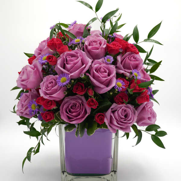Lavender and red rose bouquet in a clear square vase