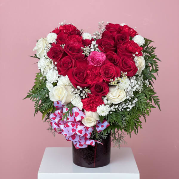Heart-shaped bouquet of red and white roses in a dark vase