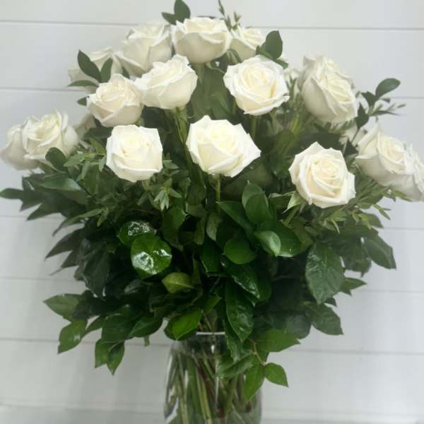 Tall arrangement of white roses in a clear glass vase
