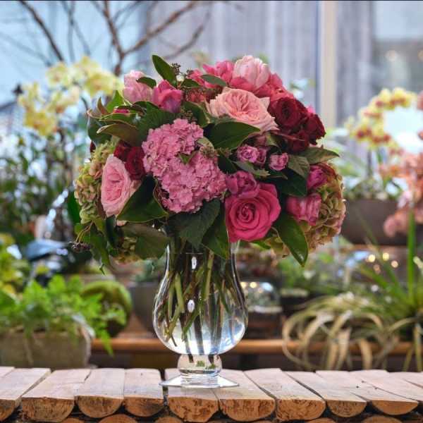 Pink and burgundy flower bouquet in a clear glass vase
