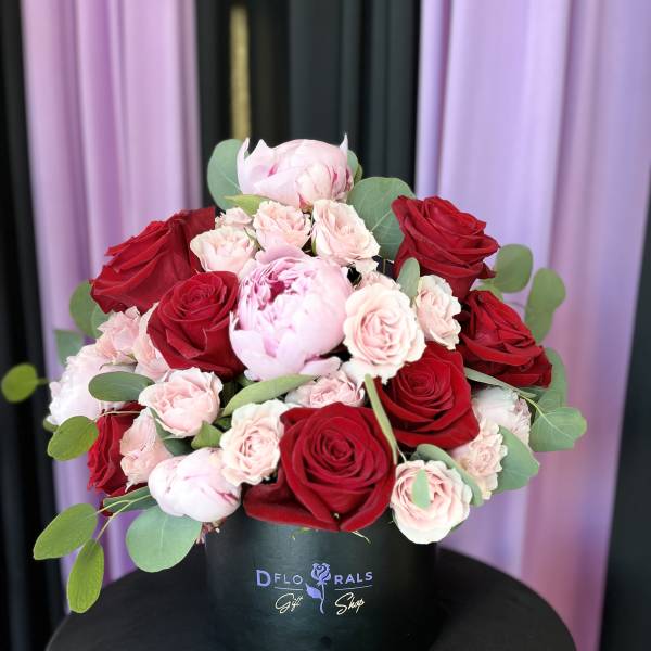 Red and blush roses arranged in a black hat box
