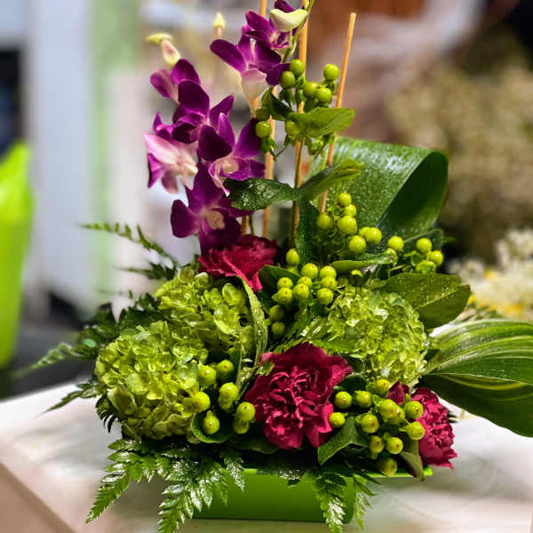 Purple orchids and green hydrangeas in a low rectangular container