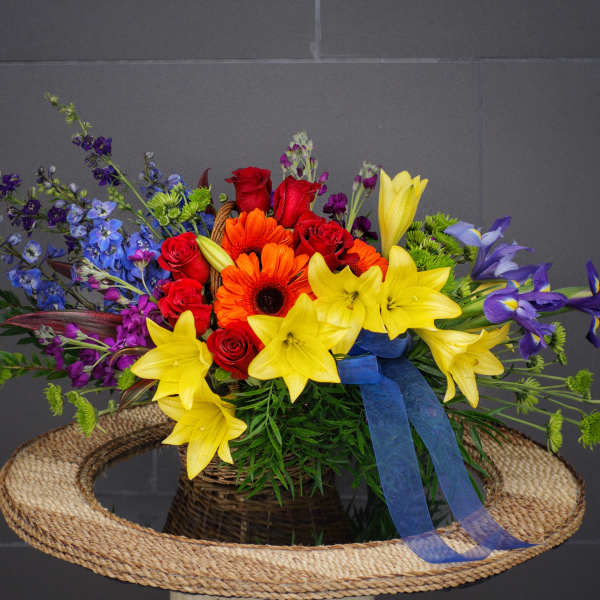 Colorful bouquet of roses, lilies, and daisies in a woven basket