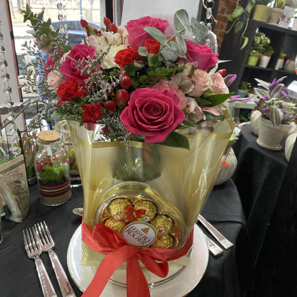 Pink rose bouquet with chocolates in a gold wrap and red ribbon