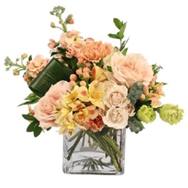 Peach and cream bouquet in a clear square vase