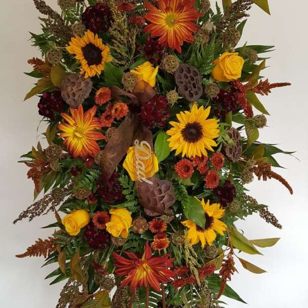 Tall standing floral spray with sunflowers, roses, and autumn foliage