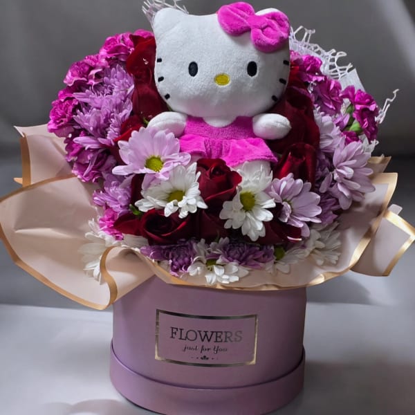 Hello Kitty plush surrounded by pink, white, and red flowers in a gift box