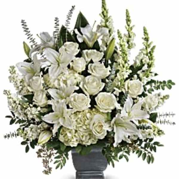 White roses and lilies arranged in a dark urn vase