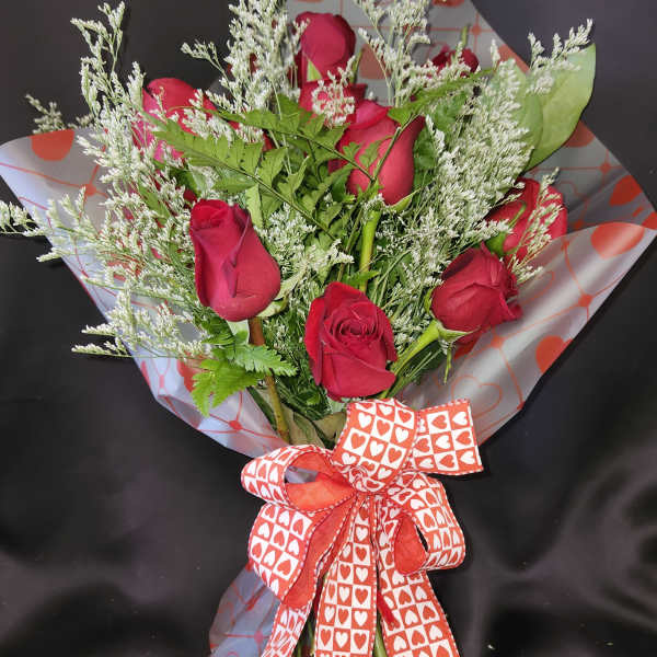 Bouquet of red roses with white filler and a heart-patterned ribbon
