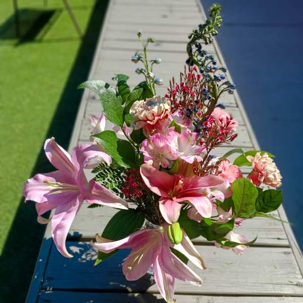 Pink lilies and mixed blooms arranged in a clear glass vase