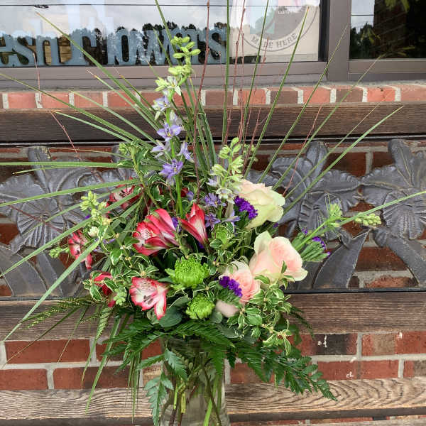 Mixed bouquet in a clear glass vase with pink, purple, and green flowers