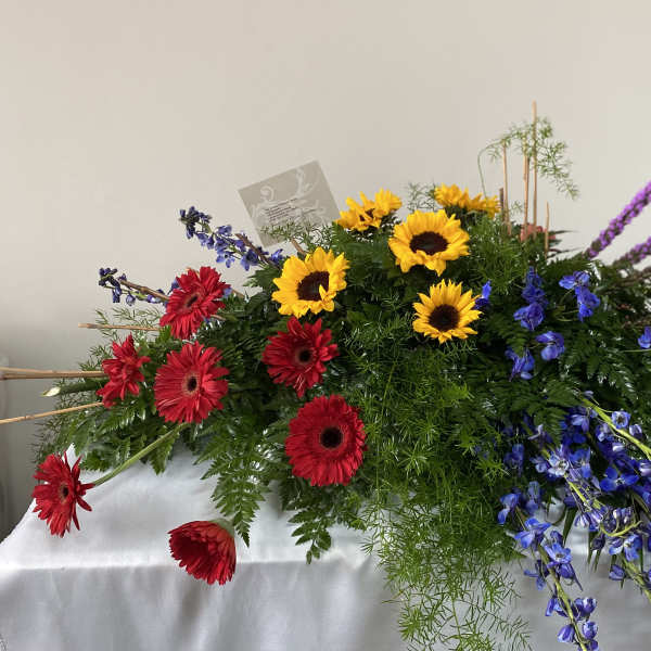 Large mixed floral arrangement with sunflowers, red gerberas, and purple spikes