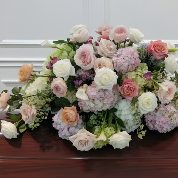 Large pastel floral arrangement with roses and hydrangeas on a polished table