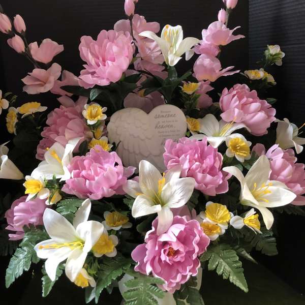 Pink and white floral arrangement with an angel plaque in a white vase