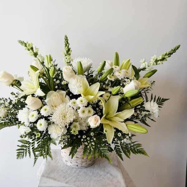 White lilies and roses arranged in a white basket