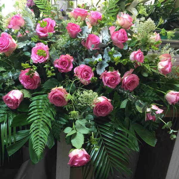 Large arrangement of pink roses with lush greenery