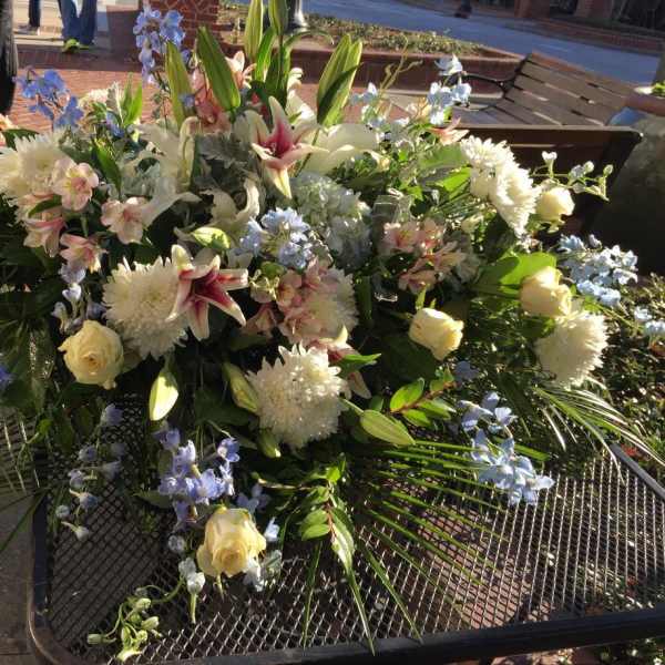 Large mixed floral arrangement with white lilies, roses, and blue flowers