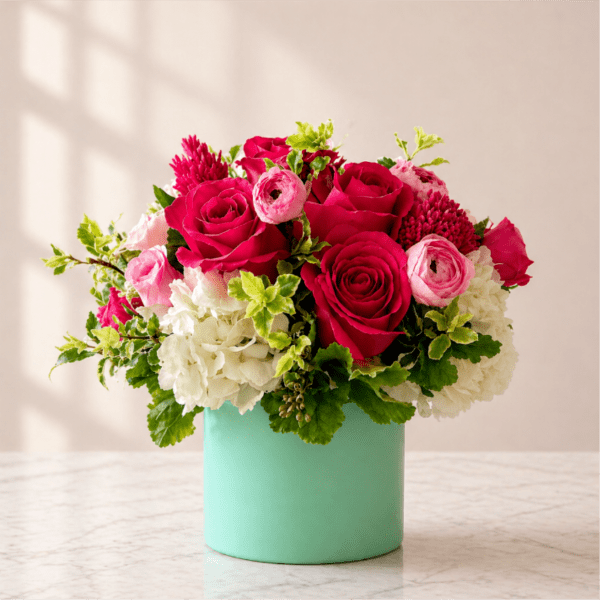Pink and white flower arrangement in a mint green vase