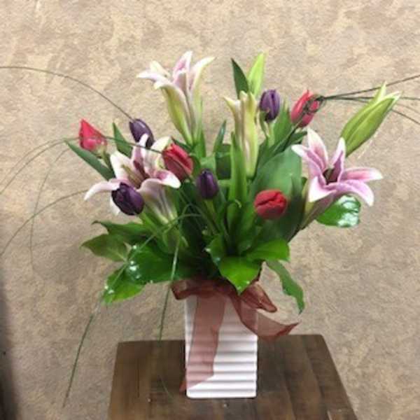 Bouquet of pink, purple, and white lilies in a white vase