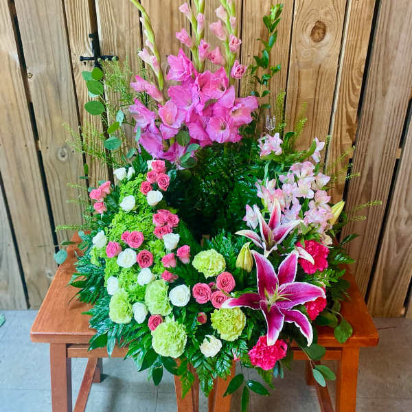 Tall pink floral arrangement with lilies and roses on a wooden table