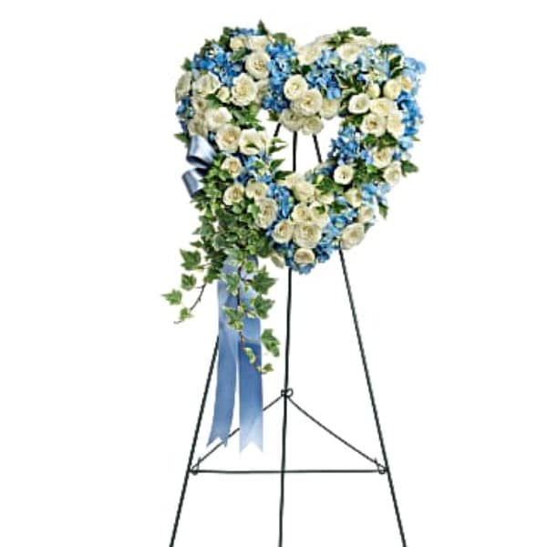 Heart-shaped floral wreath on a standing easel with blue and white flowers