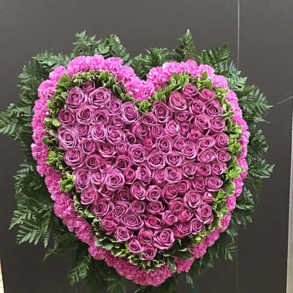 Heart-shaped pink rose funeral spray on an easel