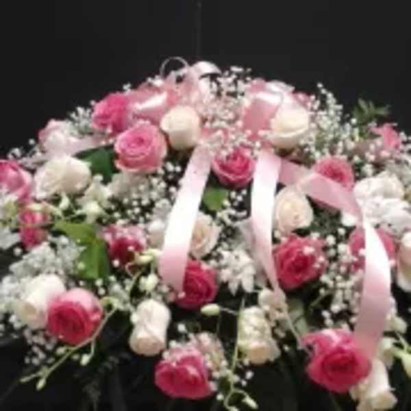 Pink and white rose arrangement with baby’s breath and ribbon