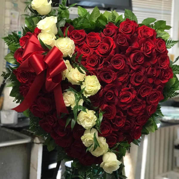 Heart-shaped bouquet of red and white roses with a red ribbon