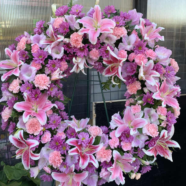 Large pink and purple floral wreath on a stand