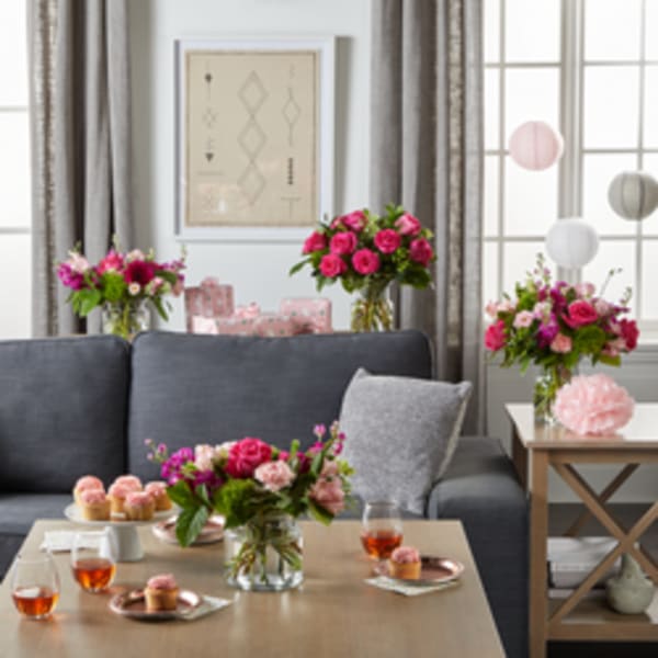 Pink rose and carnation arrangements on a table in a living room