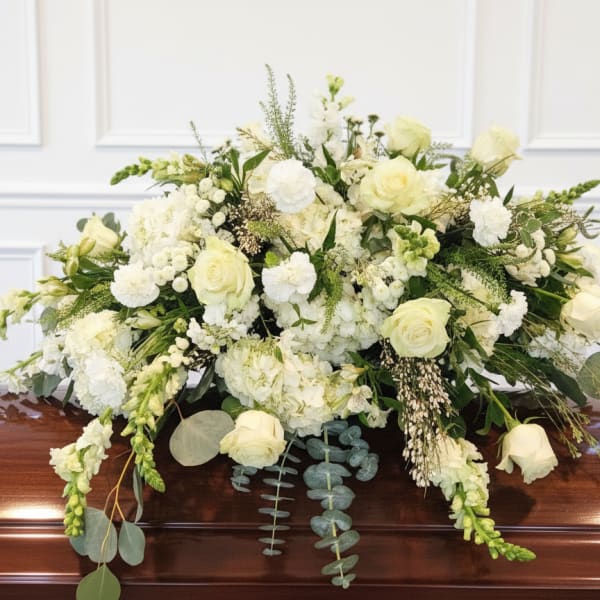 White floral casket spray with roses and mixed blooms