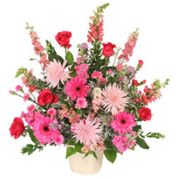 Pink and red mixed flower arrangement in a cream vase