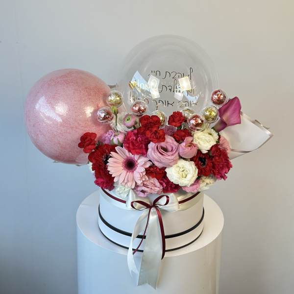 Pink and red flower arrangement in a white hat box with balloons