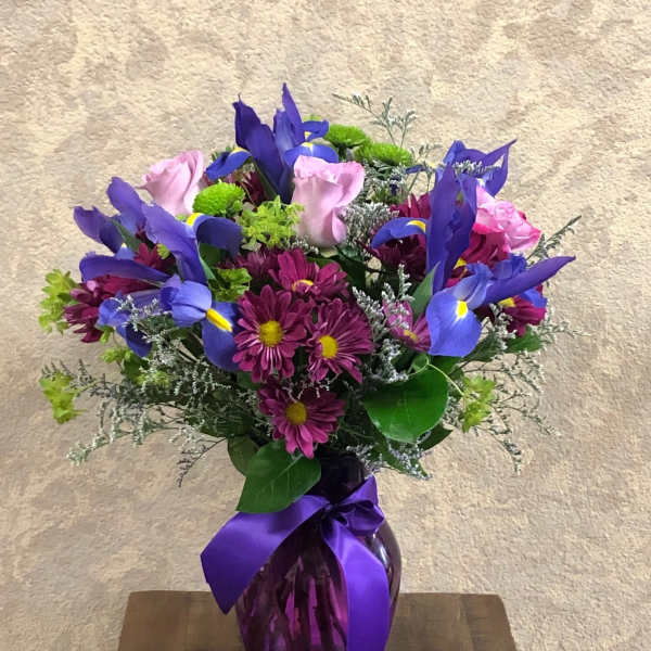 Bouquet of purple irises and pink daisies in a purple vase