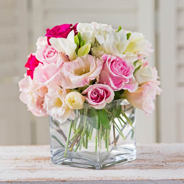 Pink and white rose bouquet in a clear square vase