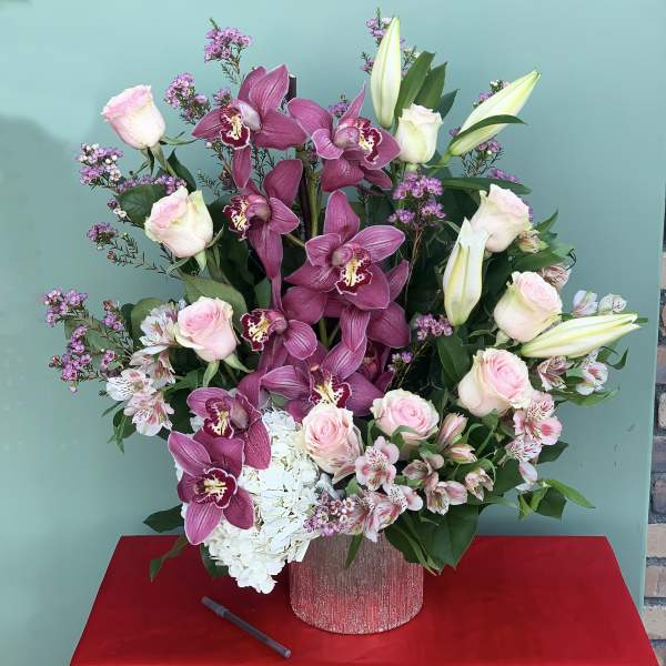 Pink orchids, roses, lilies, and white hydrangea in a glittery vase