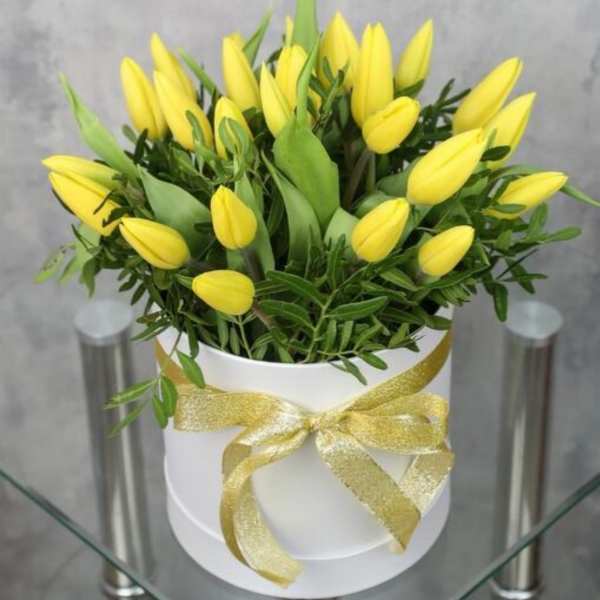 Yellow tulips in a white hatbox tied with a gold ribbon